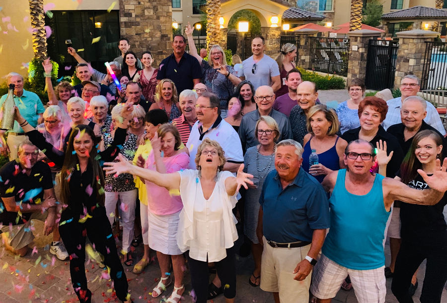 Residents of all ages cheering under confetti at an outdoor community party